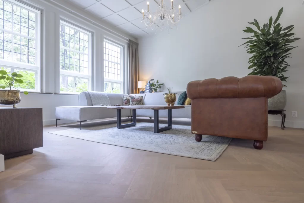 Woonkamer met een lichte eiken visgraatvloer en leren fauteuil, project Tivoli