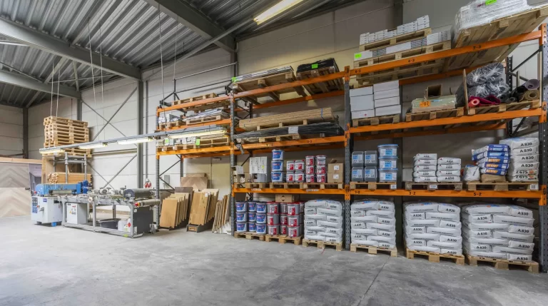 Magazijn van de werkplaats met stellingen vol vloeren, lijmen en egalines